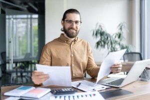 persona revisando documentos con computadora abierta