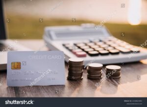 tarjeta bancaria y monedas sobre mesa madera